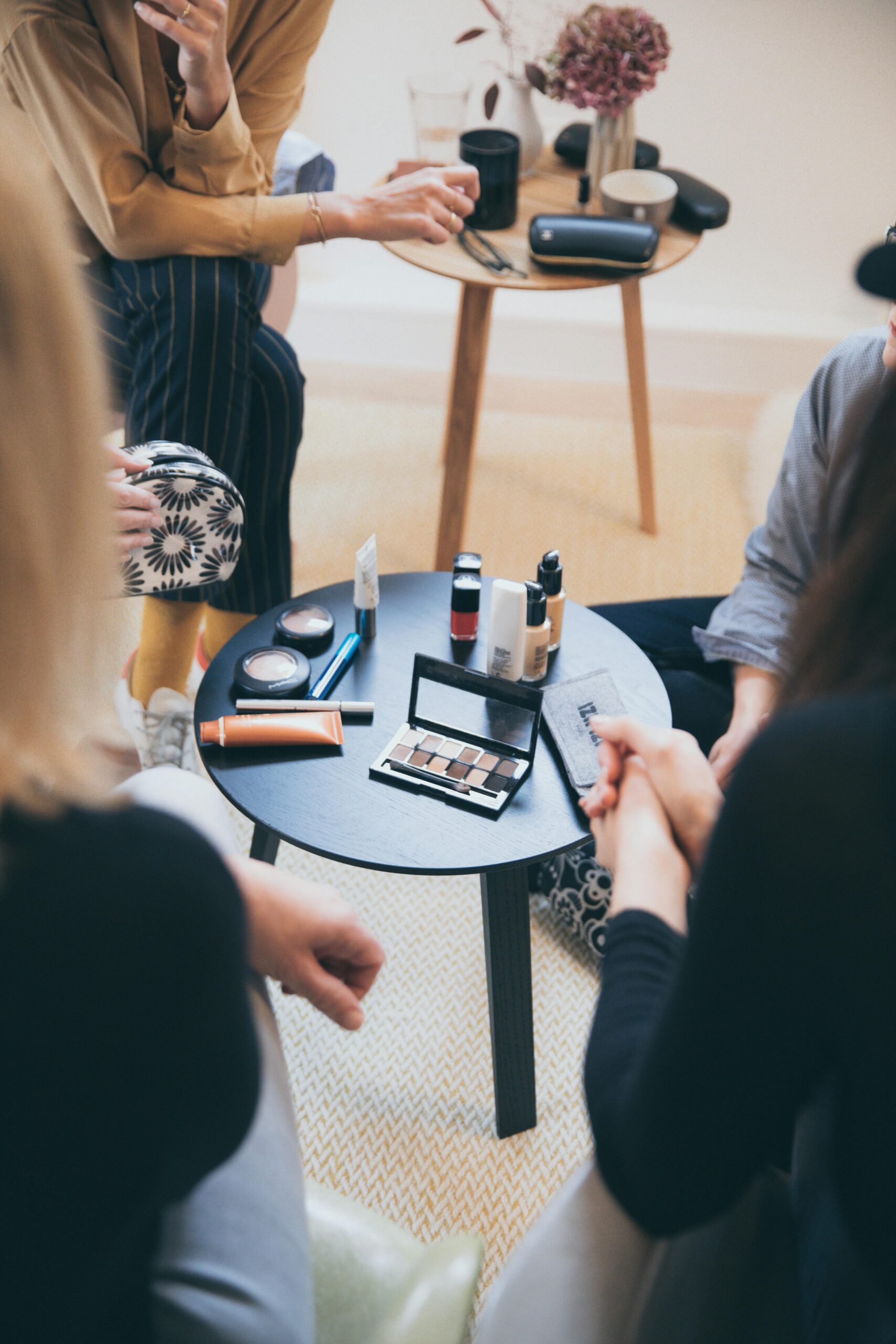 Women gathered around a table applying cosmetics, fostering a collaborative workspace.
